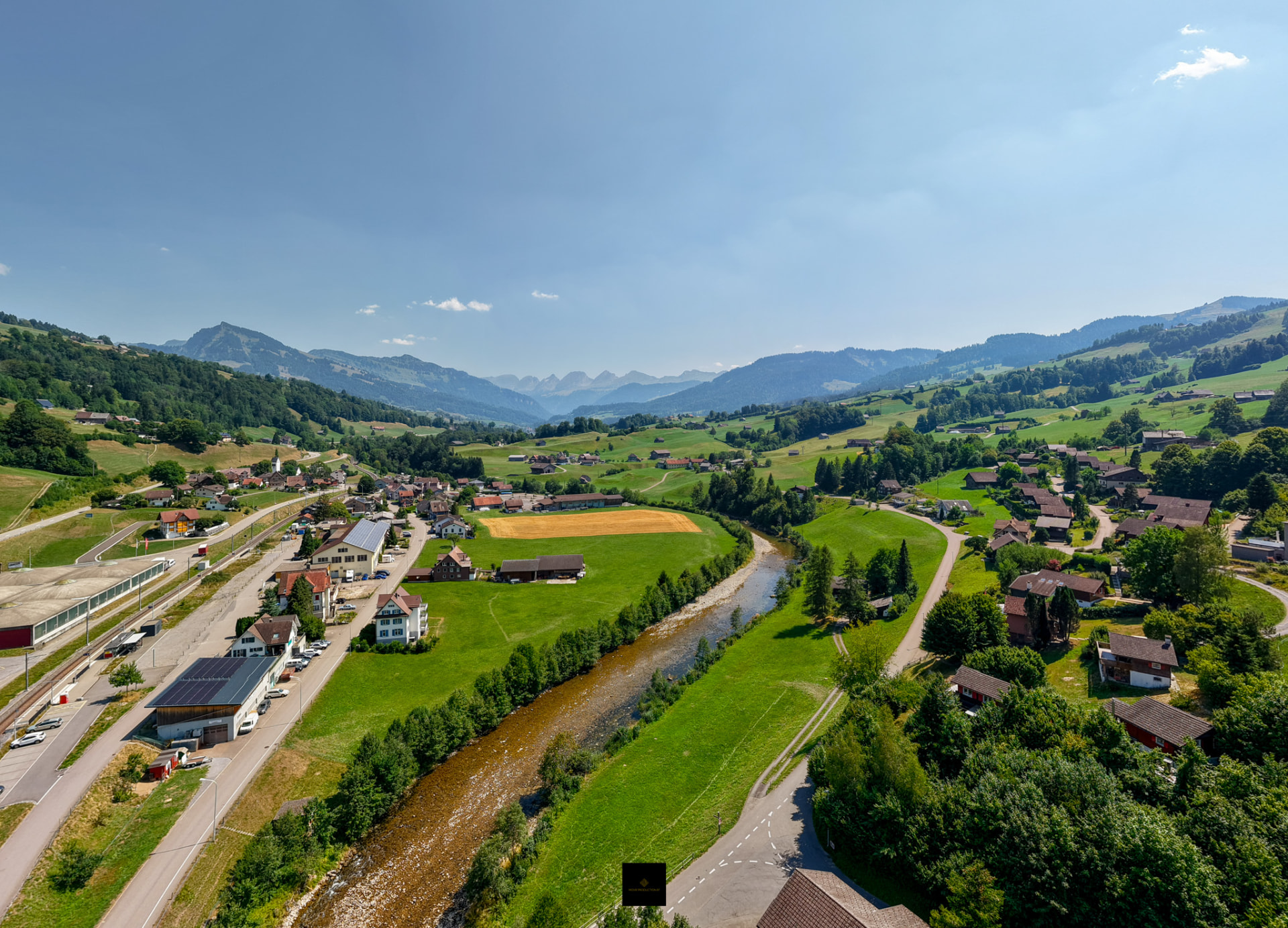 Drohnenaufnahme eines Dorfes im Tal mit Fluss und Bergen