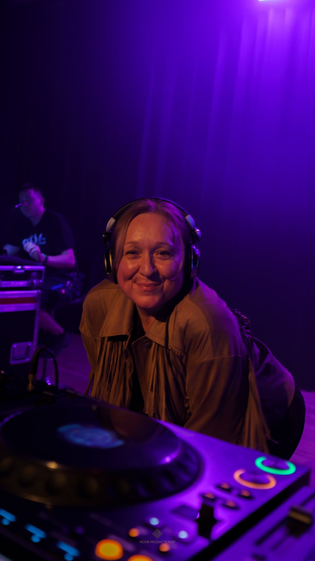 DJ mit Kopfhörern am Turntable im lila Licht